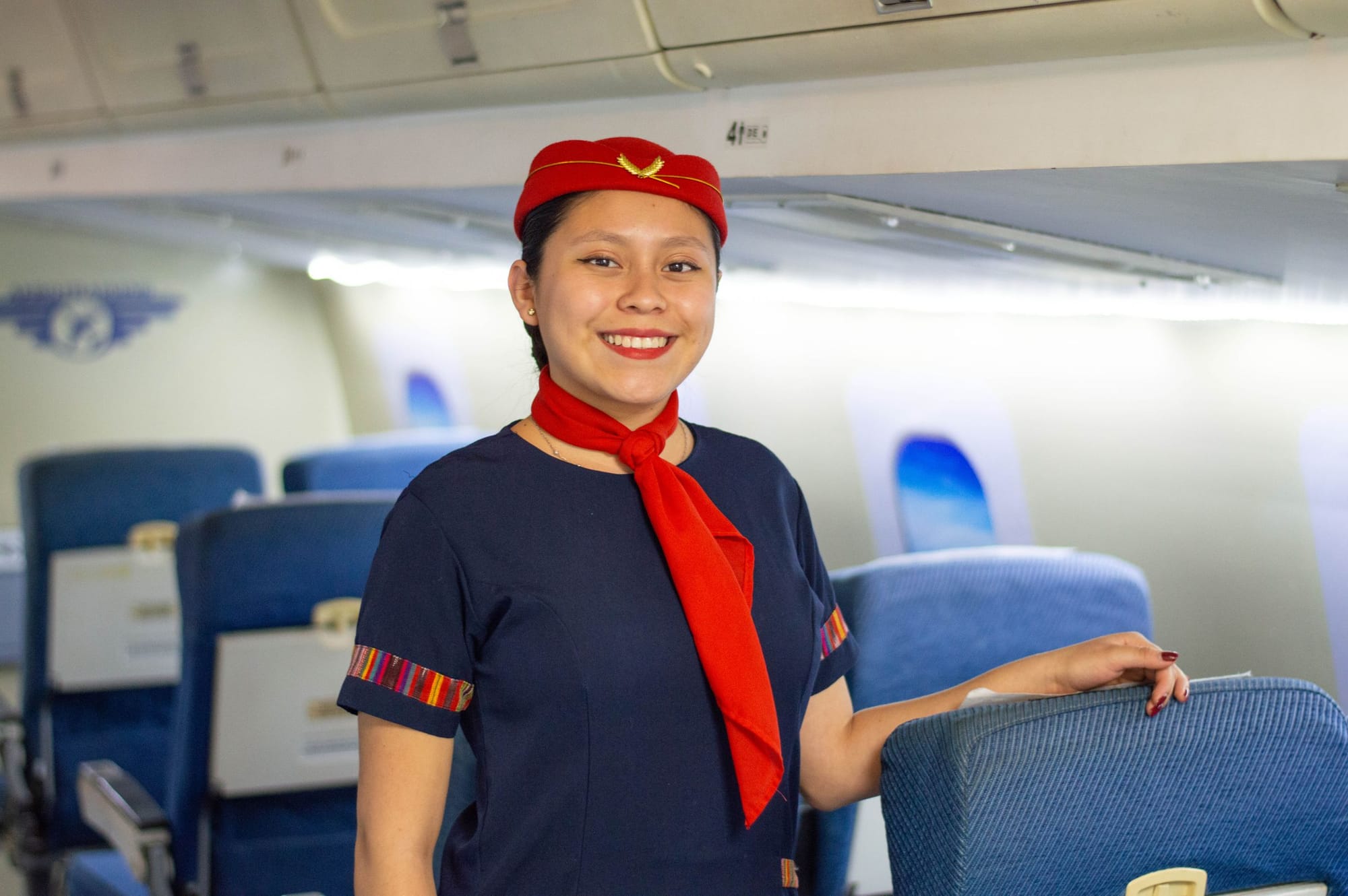 A smiling flight attendant in uniform in an airliner cabin