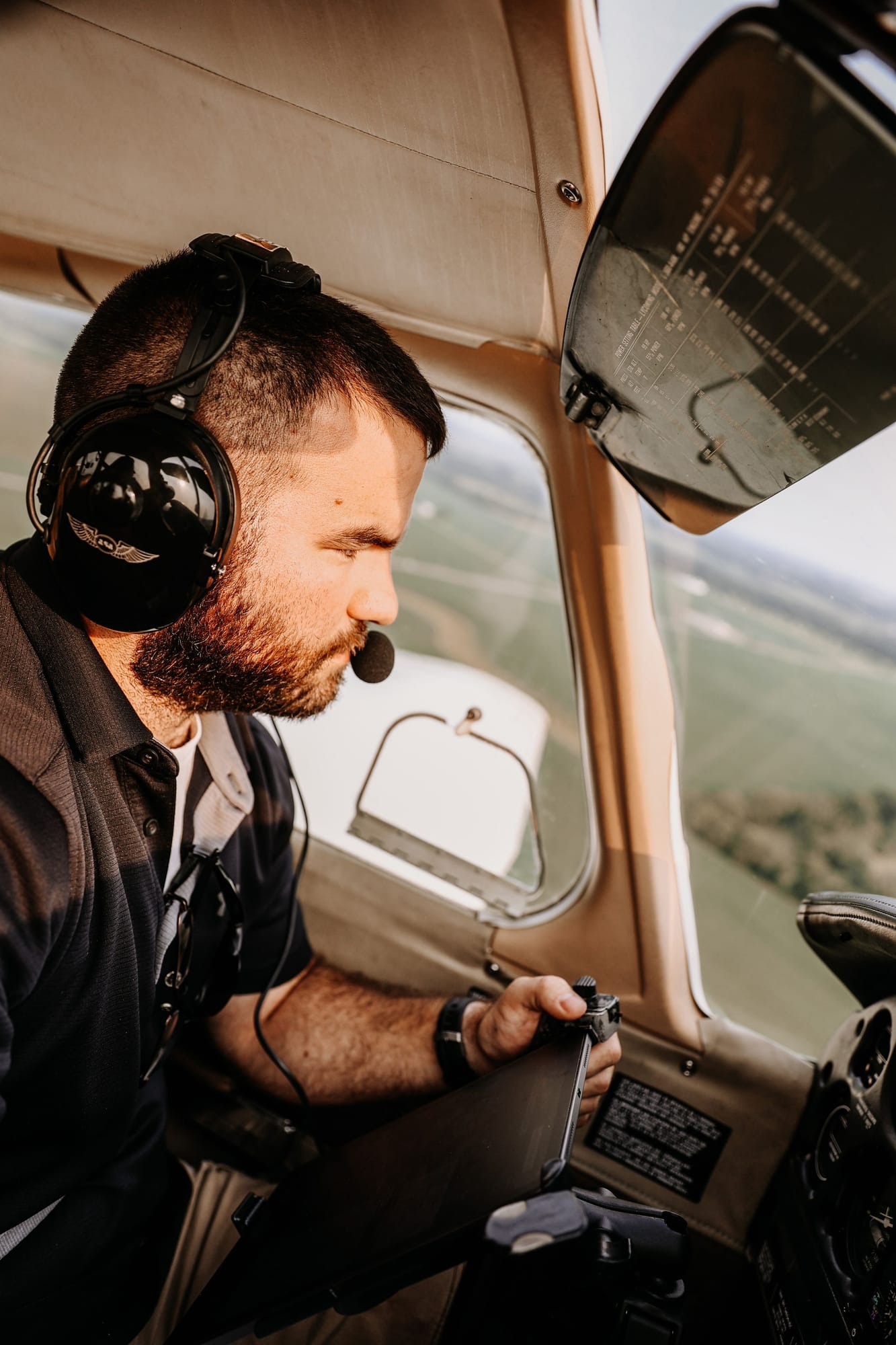 A pilot with a headset flying a small training aircraft