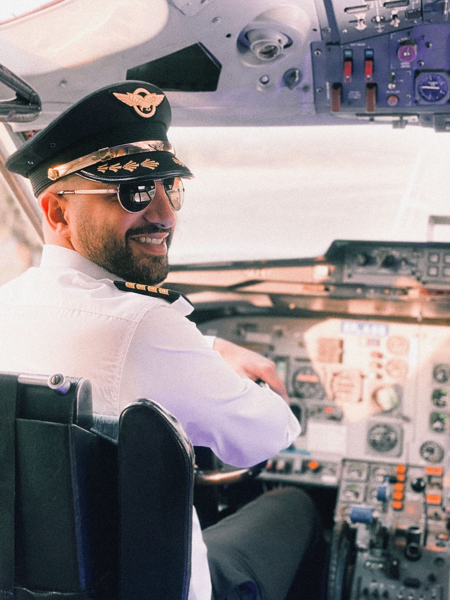 A smiling pilot in uniform in the cockpit
