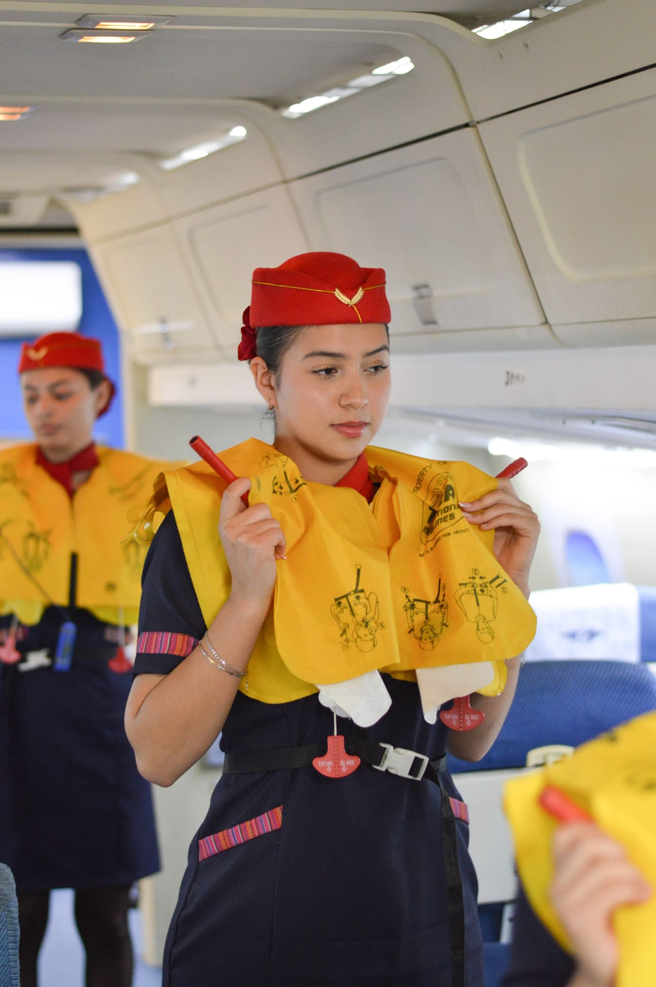 Flight attendants demonstrating life jackets in an airliner cabin
