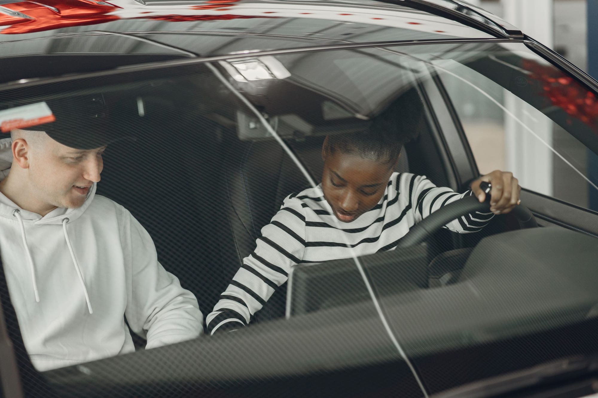 A learner driver at the wheel talking with her instructor