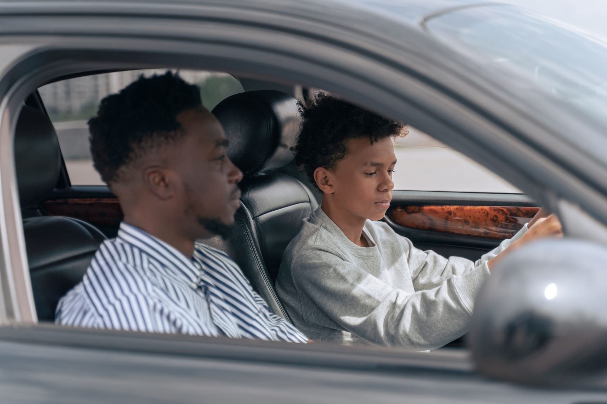 A driving instructor beside a young learner at the wheel