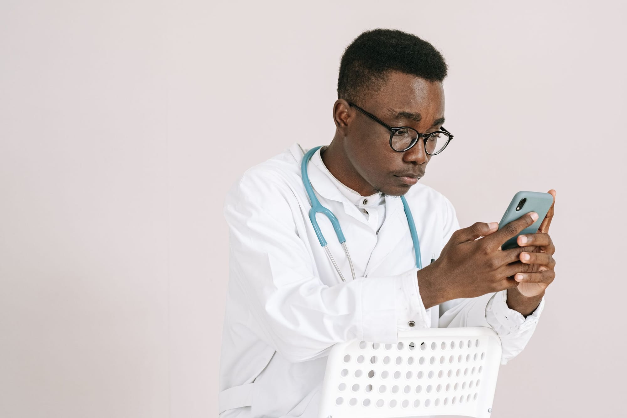 A doctor in a white coat checking his phone