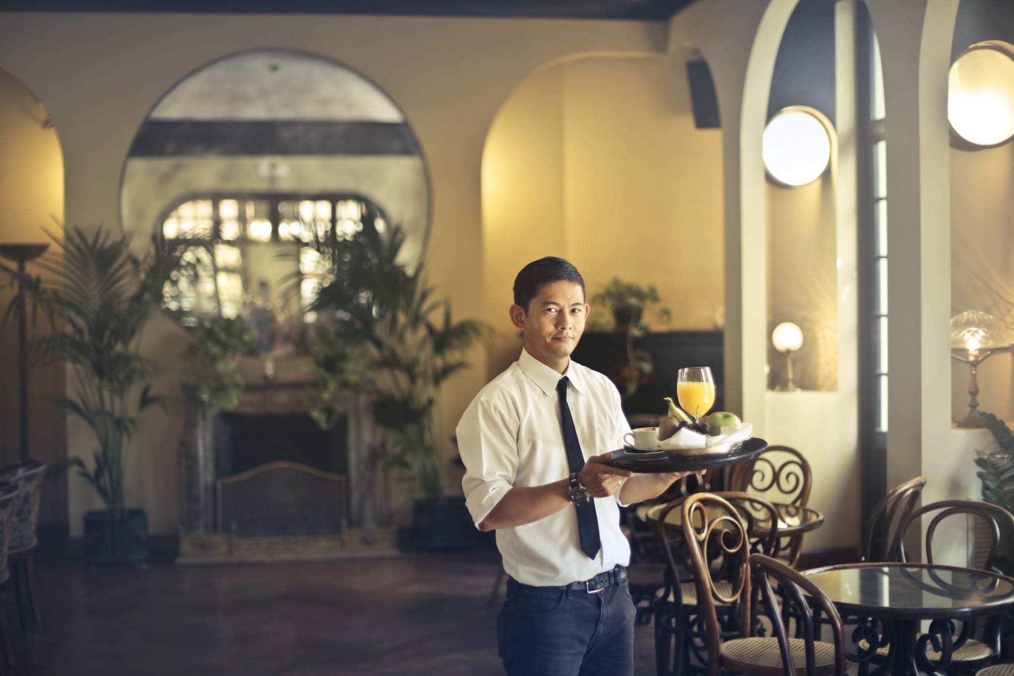 A waiter carrying a tray of drinks through a restaurant