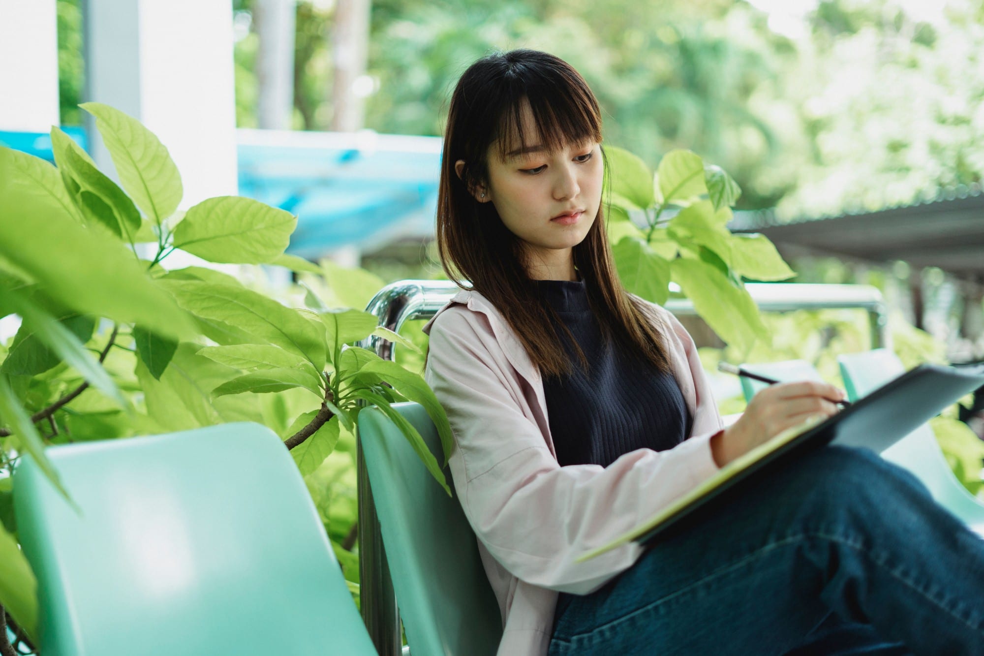 A student writing in her notebook among green plants