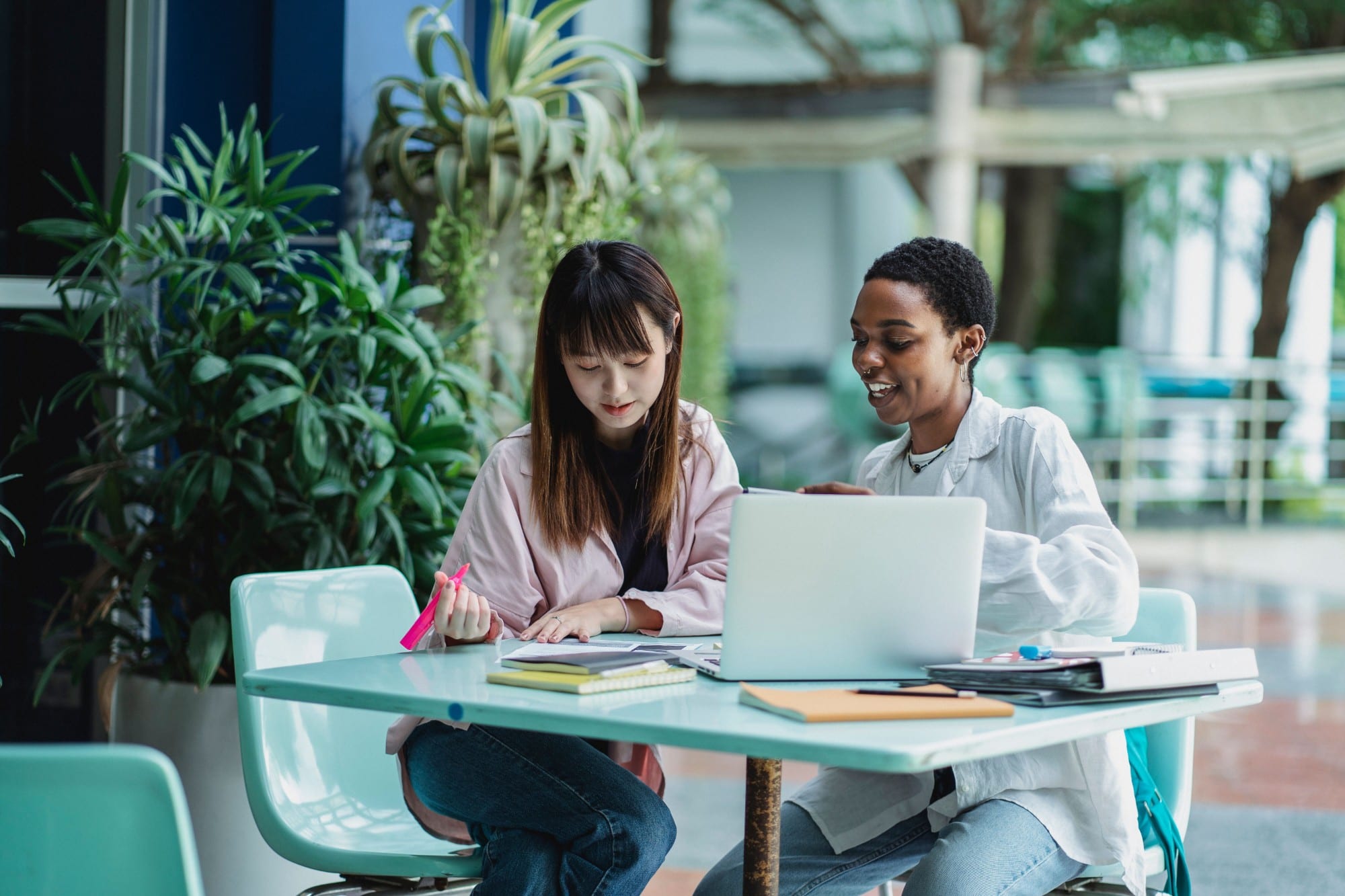 Two students at a table with a laptop and notebooks